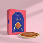 A pink and blue box of Sr. Kitchen Brand's Classic Athirasm (pudina) shown next to a single round baked good on a gold plate, set against a soft pink background with artistic shadows.