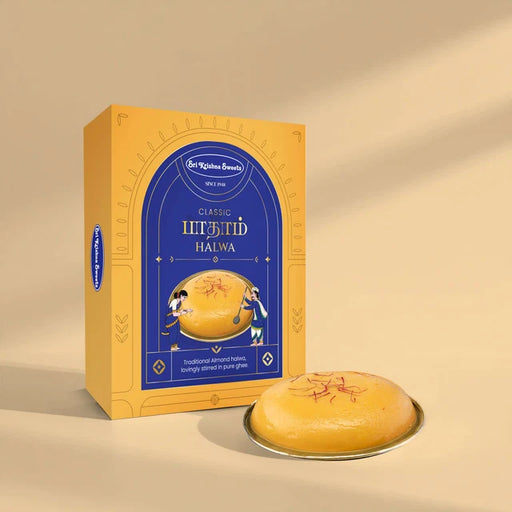 A yellow and blue box of  Classic Halwa next to a round golden halwa on a small plate, set against a warm beige background with soft shadows.