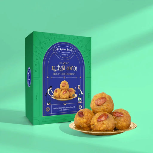 A green and blue box of Sr. Kitchen Brand Classic Boondi Laddoo next to a small gold plate holding four golden-brown fried sweets with red chutney, set against a mint green background.
