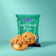 A green bag of Classic Chettinad Vellai snack, shown with two copper bowls filled with golden-brown chettinad balls on a solid teal background.