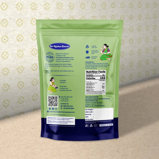 A stand-up pouch of Sit Kshitar Sweets back view, featuring a light green upper half and a dark blue lower half, with illustrations and product details printed on it, set against a patterned beige background.