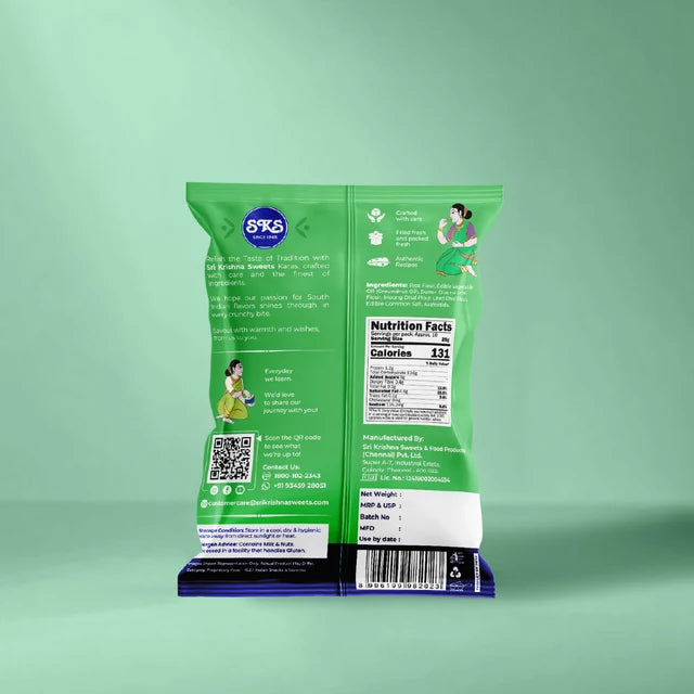 The back of a green snack bag standing upright on a dark blue base, showing printed text, a nutrition facts panel, QR code, and illustrations, against a mint green background.