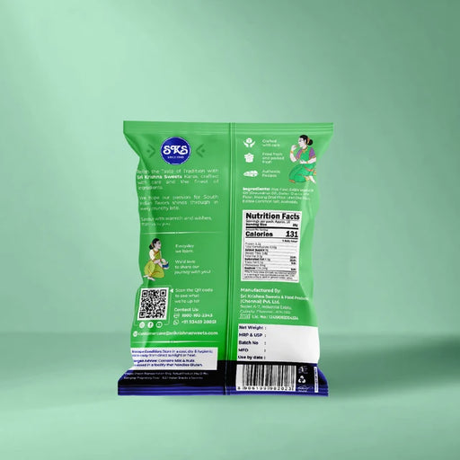 The back of a green snack bag standing upright on a dark blue base, showing printed text, a nutrition facts panel, QR code, and illustrations, against a mint green background.