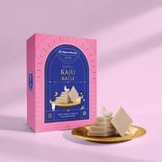 Pink box of Classic Kaju Katli with a gold plate of Kaju Katli on a pink background